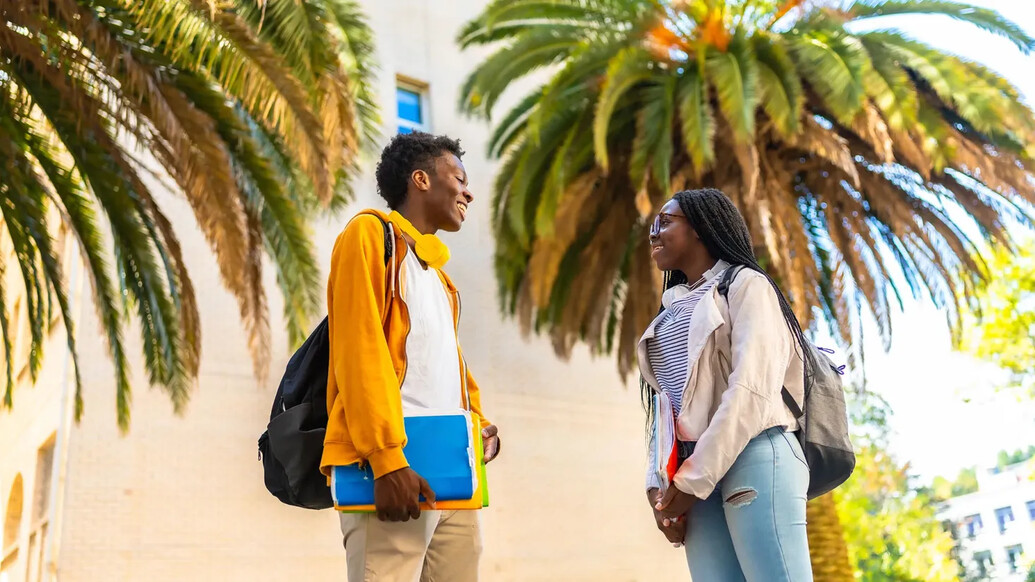 Two students in Miami in front of palm trees