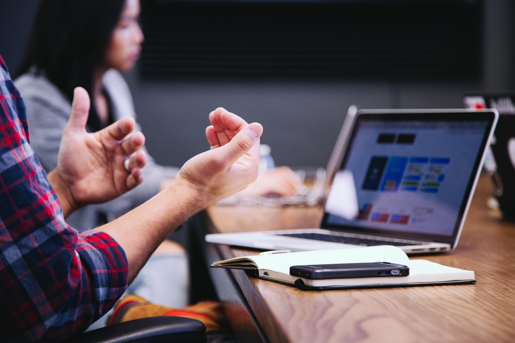 Man at a laptop, gesturing with hands