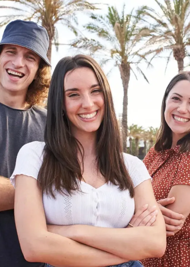 Group of smiling students in front of palm trees