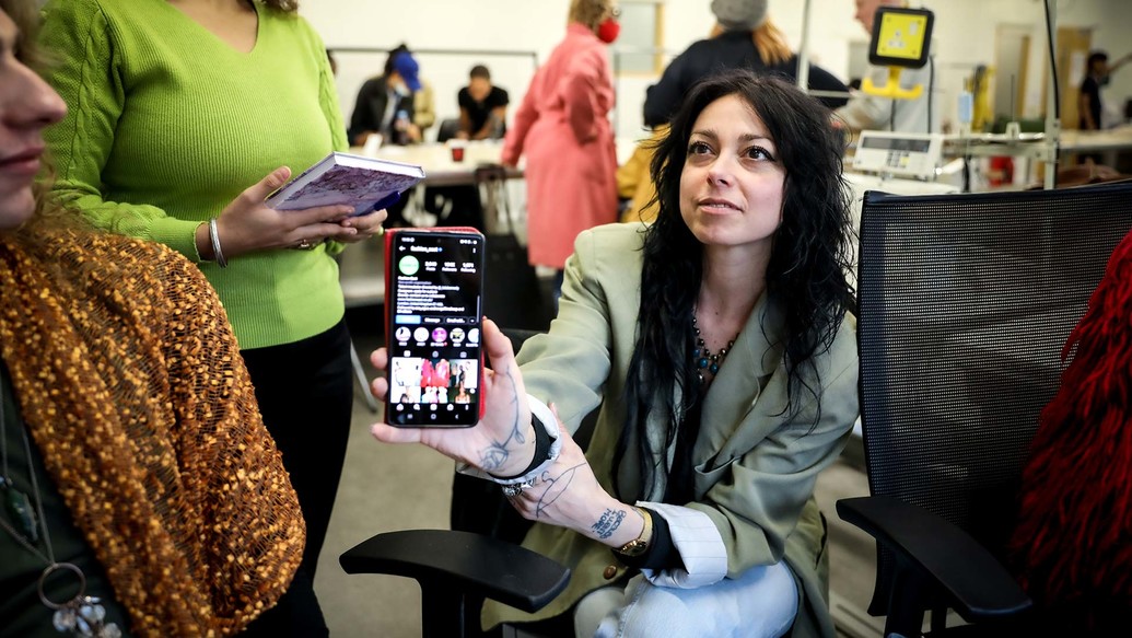 A woman holds up her phone. An Instagram account is on screen